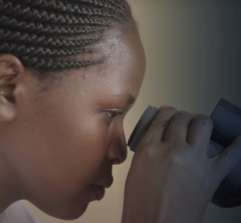 A young girl looks through a microscope