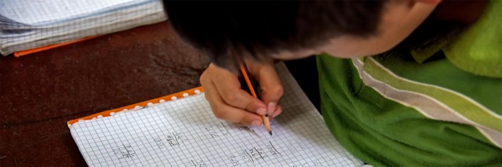 A schoolboy writing in a notebook