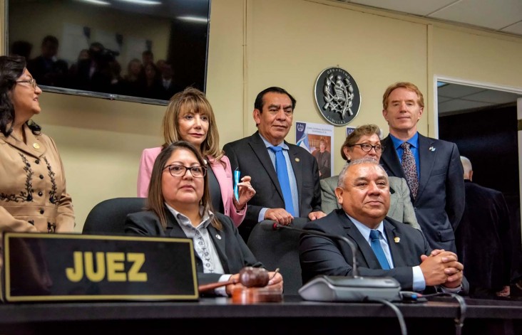 Guatemalan justice officials pose for a photo behind a desk during a news conference.