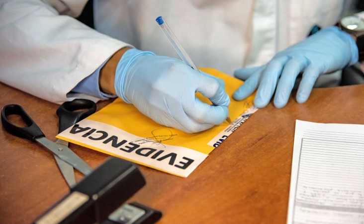 An evidence technician seals evidence in an envelope