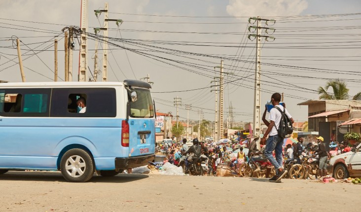 A blue taxi, a man walking and crisscrossing power lines in Luanda.