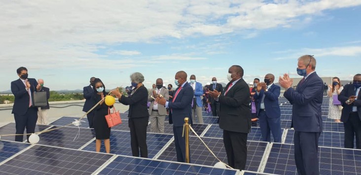 Participants standing between solar panels at the launch of the Rooftop Solar program in Botswana