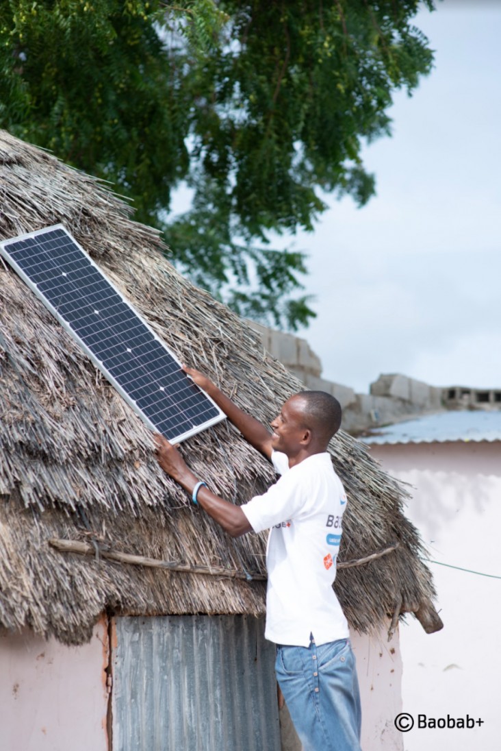 A Baobab Plus agent putting solar panel on a house