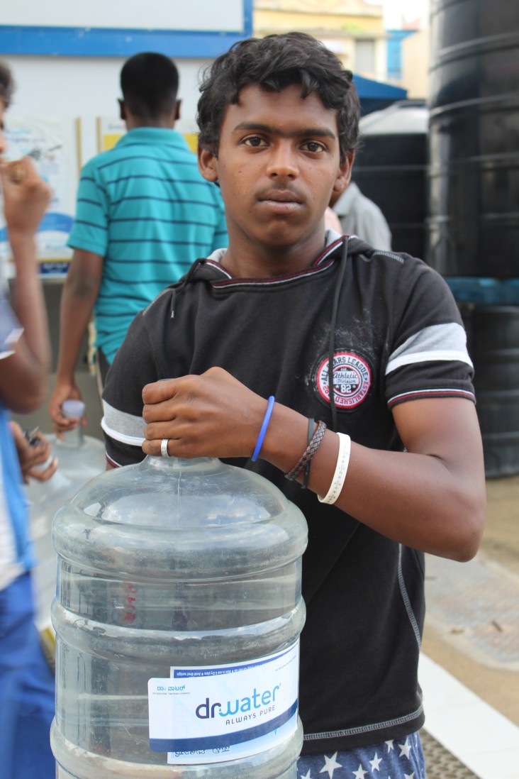 A slum dweller in Bangalore’s Lingarajpuram district holds a can of purified water.