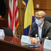 A man seated at a table speaks into a microphone.